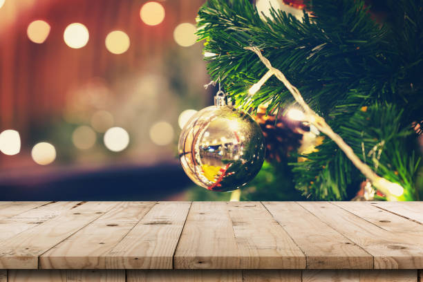 istock Empty wood table and christmas pine cones hanging from Christmas tree with display montage for product. 1054737076