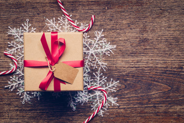 istock Christmas gift box placed and white snowflakes on wooden planks with space. 1054737200