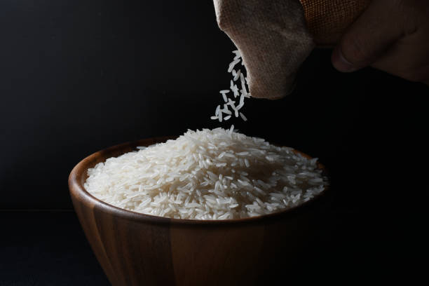 istock Pouring jasmine rice into a wooden bowl on black background 1054737730