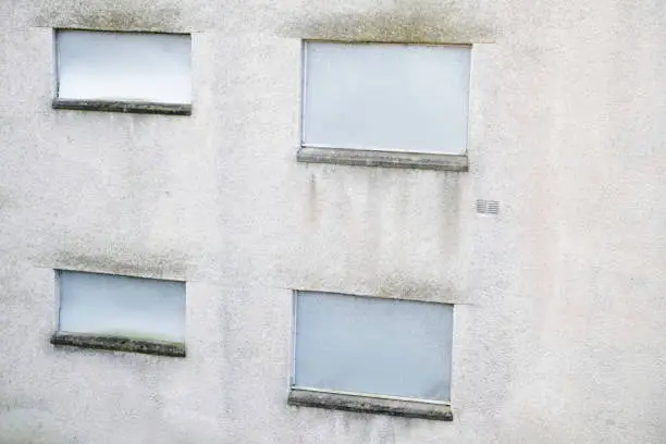 Abandoned building metal sheet board over windows dull grey dirty wall uk