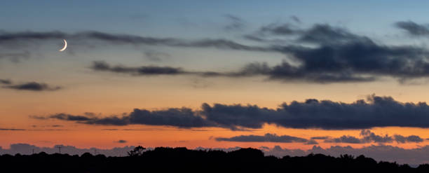 istock Sunset Silhouette With Waxing Cresent Moon and Clouds 1054745642