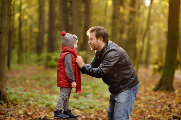 Little boy with his father during stroll in the forest. Active family time on nature. Fun with little kids in fall days