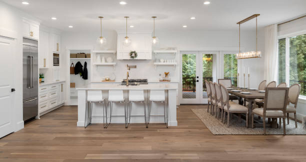 beautiful kitchen panorama in new luxury home with island, pendant lights, and hardwood floors. Also features dining room and dining room table kitchen and dining room panorama in newly constructed luxury home renovation photos stock pictures, royalty-free photos & images