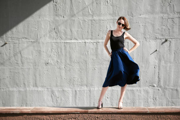 istock young girl posing against a concrete wall, dressed in black, hard light and shadows 1054757848