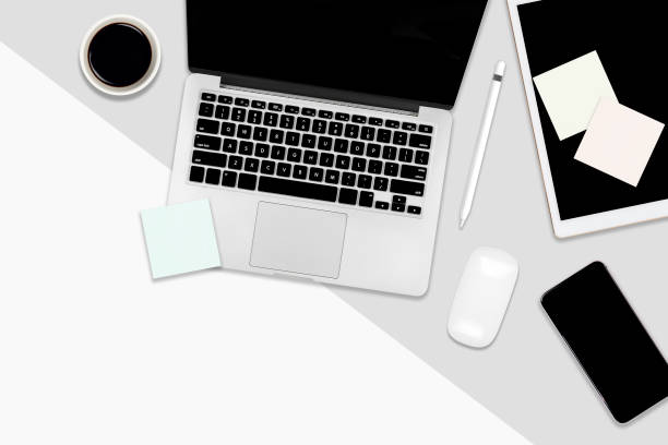 istock Flat lay office table with laptop computer, digital tablet, mobile phone and accessories on two tone white and grey background. Desktop office mockup concept. 1054758694