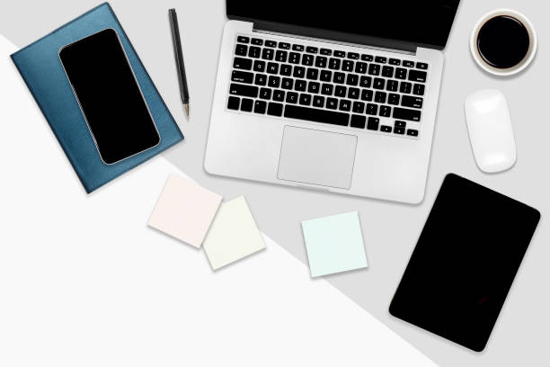 istock Flat lay office table with laptop computer, digital tablet, mobile phone and accessories on two tone white and grey background. Desktop office mockup concept. 1054758720