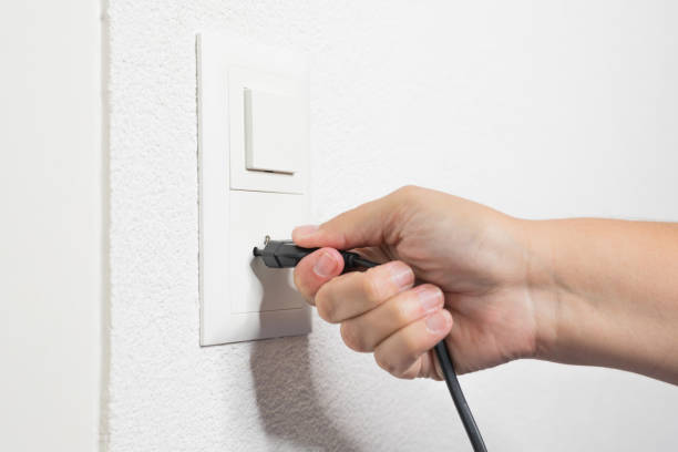 女性の手は、ソケットから黒いコードをプルします。 - electric plug outlet pulling electricity ストックフォトと画像