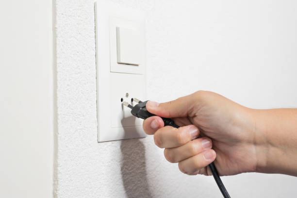 рука женщины вытаскивает черный шнур из гнезда. - electric plug outlet pulling electricity стоковые фото и изображения