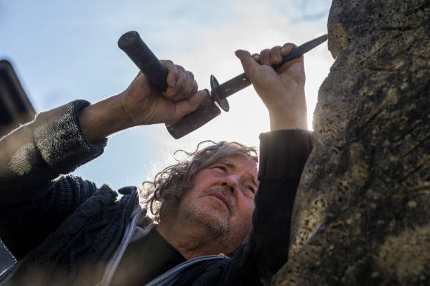 istock Bottom view of sculptor sculpting with chisel and hammer 1054761428