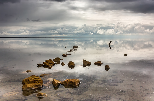 Stones and reflection of the sky in the salt lake of Elton, Russia