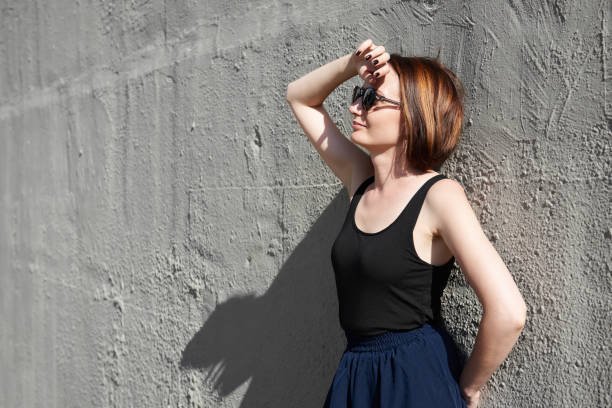 istock young girl posing against a concrete wall, dressed in black, hard light and shadows 1054762214