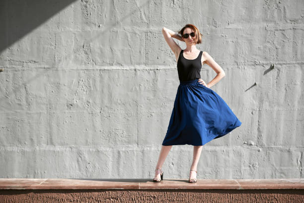 istock young girl posing against a concrete wall, dressed in black, hard light and shadows 1054763496