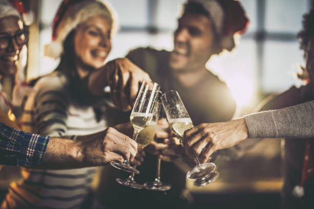 Close up of drinking champagne on New Year's party. Close up of group of happy friends having fun while pouring champagne during Christmas party. office christmas party stock pictures, royalty-free photos & images