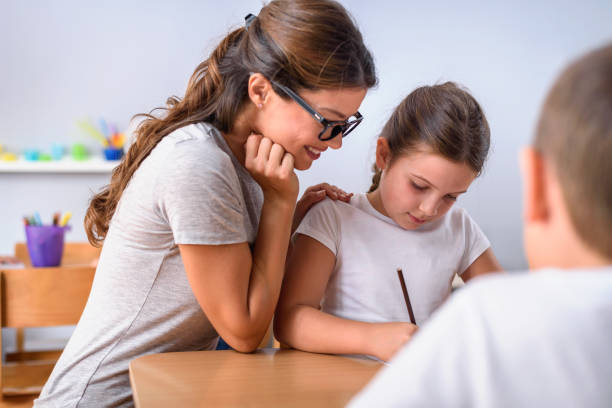 istock Children drawing with smiling preschool teacher assisting them 1054772060