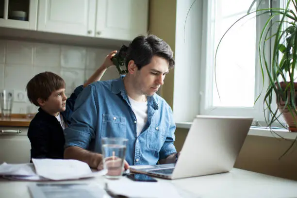 Photo of Little son disturbing working freelancer father