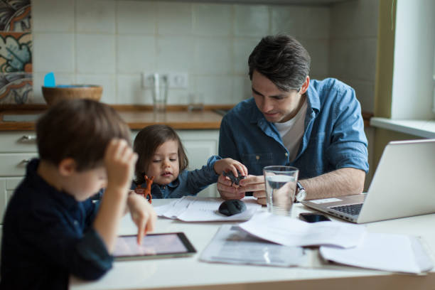 istock Young father working at home and looking after son and daughter 1054778440