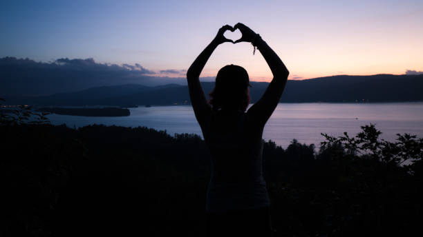 istock Heart Shape with Hands Female Hiker Watching Sunset Over Lake 1054778936