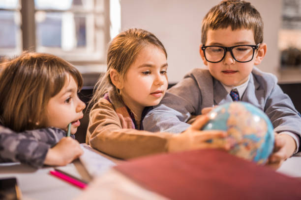 istock Three little explorers looking at the globe in the office. 1054778938