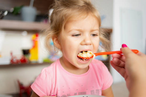 istock Cute little girl is feeding by her mom. 1054780854