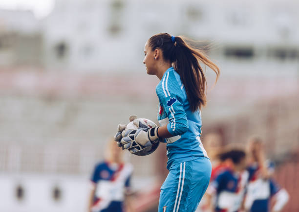 gardien de but football féminin avec un ballon sur un stade. - fitness goal photos et images de collection