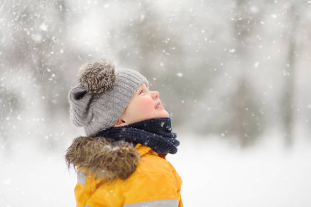 istock Cute little boy in yellow winter clothes walks during a snowfall 1054784984