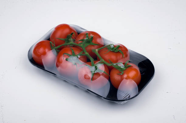 Plastic tray with red cherry tomatoes with sepals isolated on the white background. Tomato pile. Ripe and fresh organic vegetables harvested from local farmers. Clipping path. Top view. Copy space.