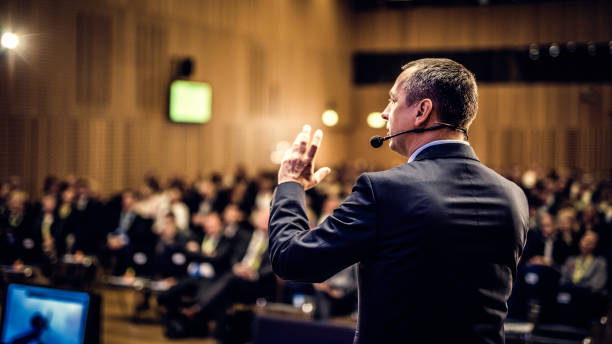 vista posterior de un coach motivacional dando un discurso - conferencehall fotografías e imágenes de stock