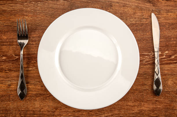 istock kitchenware in the form of a white plate, fork and knife top view 1054786292