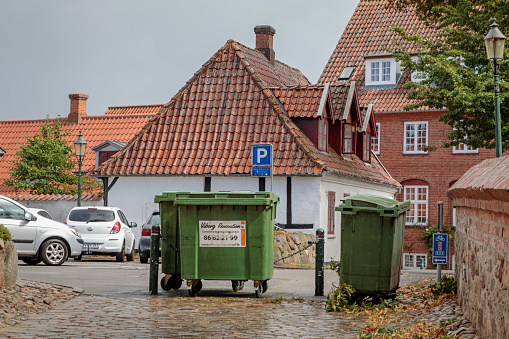 Sortebrødre Kirke Stræde, Viborg, Denmark - August 10, 2018: Garbage container and parked cars in the back space of the the shopping district