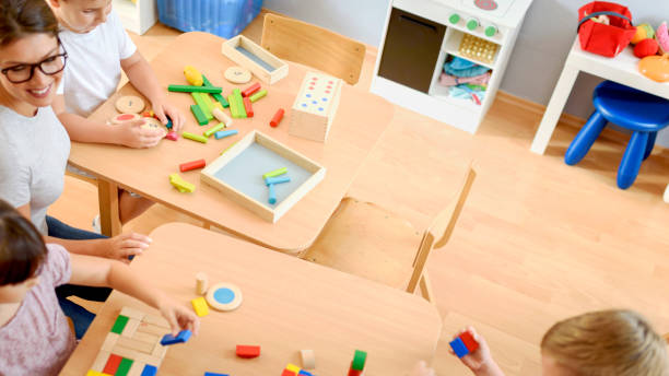 istock Preschool teacher with children playing with didactic toys 1054792188