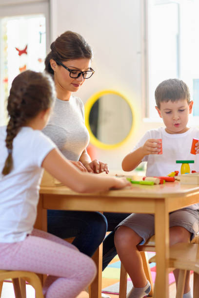 istock Preschool teacher with children playing with didactic toys 1054792244