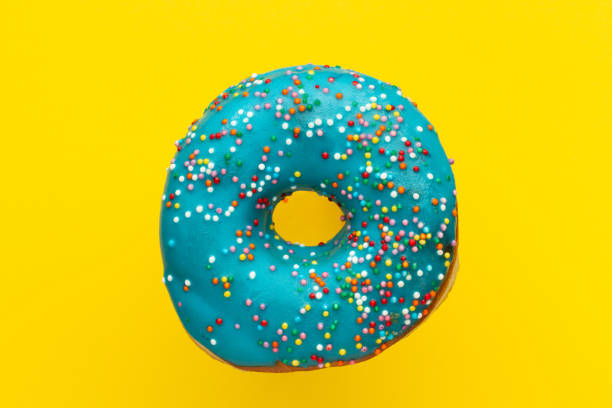istock Donut blue with sprinkles isolated on yellow background, close-up 1054794410