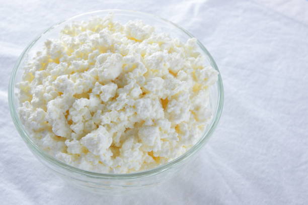 istock Cottage cheese. Cottage cheese on white background. Soft cheese in glassware on white napkin. Dairy product for breakfast. Copy space 1054796256