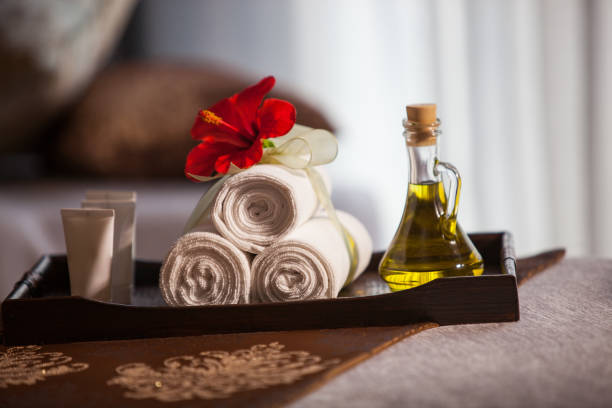 istock Spa aroma therapy preparation setting - massage oil, message cream, towels and red spring flower 1054811680