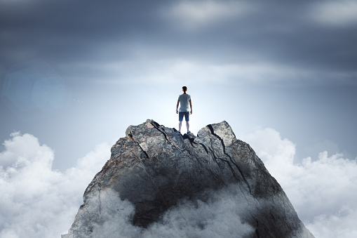 Businessman standing on abstract mountain on sky background. Promotion and leader concept