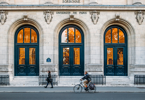 Paris, France - Oct 14, 2018: Pedestrian and cyclist with outside facade of the pretigious University Sorbonne in Paris, France