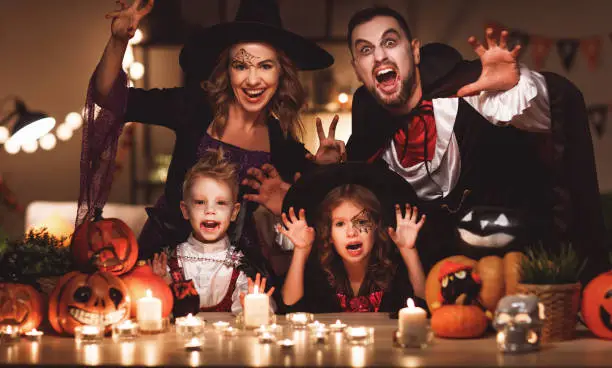 Photo of happy family mother father and children in costumes and makeup on  Halloween in dark home