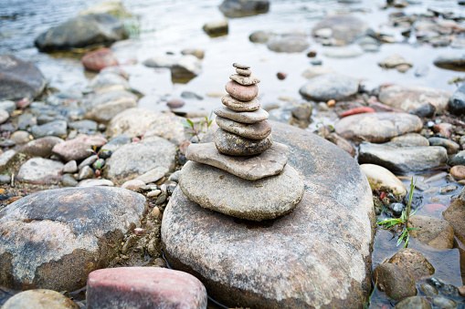 Stack of Balanced Rocks Cairn - Smooth rocks piled into cairn along waters edge symbolizing balance and harmony.