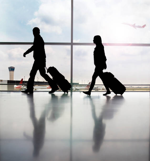 silhouette de deux passagers marchant dans le couloir de l’aéroport avec des bagages - airport usa business ohare airport photos et images de collection