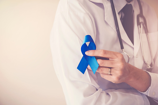 Manos del médico con cinta azul, la diabetes y la concienciación sobre el cáncer colorrectal photo