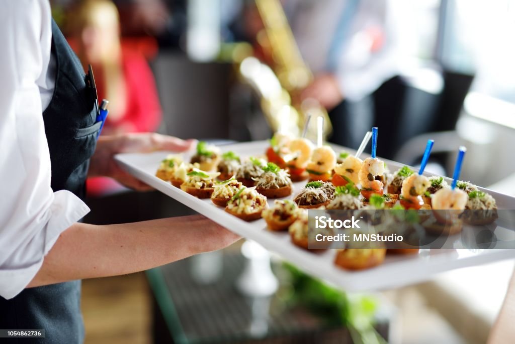 Waiter carrying plates with meat dish Waiter carrying plates with meat dish on some festive event, party or wedding reception Food And Drink Industry Stock Photo