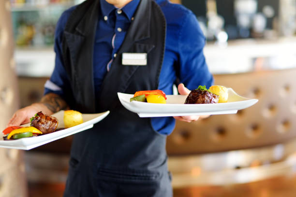 istock Waiter carrying plates with meat dish on some festive event 1054862750