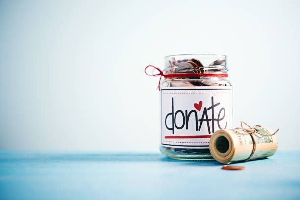 istock Donation money jar filled with coins and money roll 1054862902