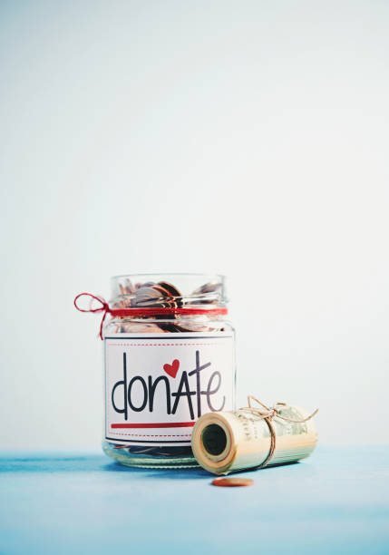 istock Donation money jar filled with coins and money roll 1054862904