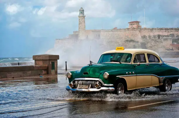 Old car in the middle of a storm through Havana's boardwalk.