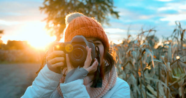 istock Beautiful Young Woman Taking picture with Digital Camera at Sunset 1054874652