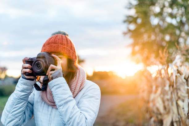 istock Beautiful Young Woman Taking picture with Digital Camera at Sunset 1054889256