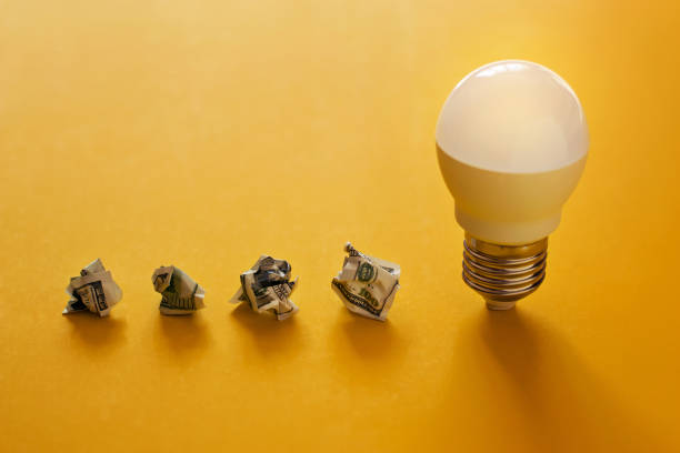 istock Lamp and crumpled dollar bills in a row on yellow background 1054899116