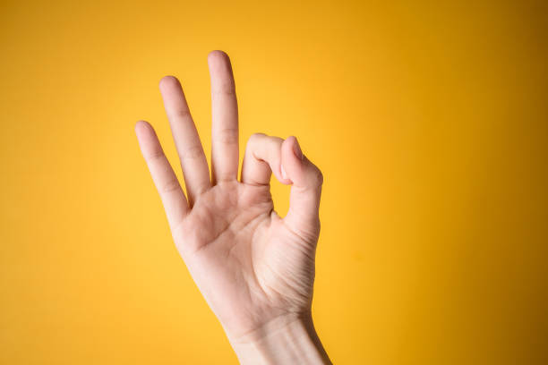 istock woman hand shows gesture okay on yellow background 1054899184