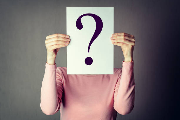 anonymous woman covering face with paper portrait of casual anonymous woman covering face with paper showing question mark. uncertainty photos stock pictures, royalty-free photos & images